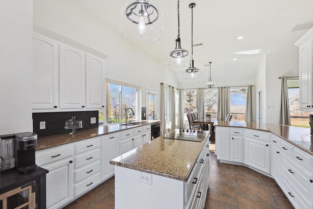 kitchen with a sink, dark stone counters, plenty of natural light, and black appliances