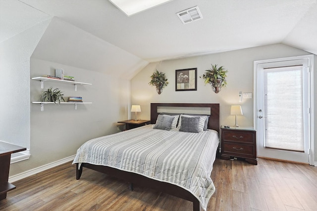 bedroom featuring lofted ceiling, visible vents, and wood finished floors