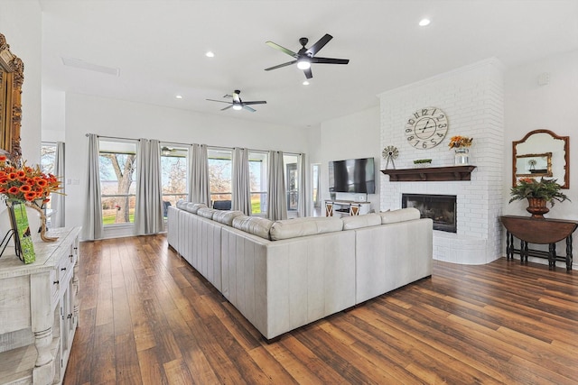 living room with dark wood-type flooring, recessed lighting, a brick fireplace, and a ceiling fan