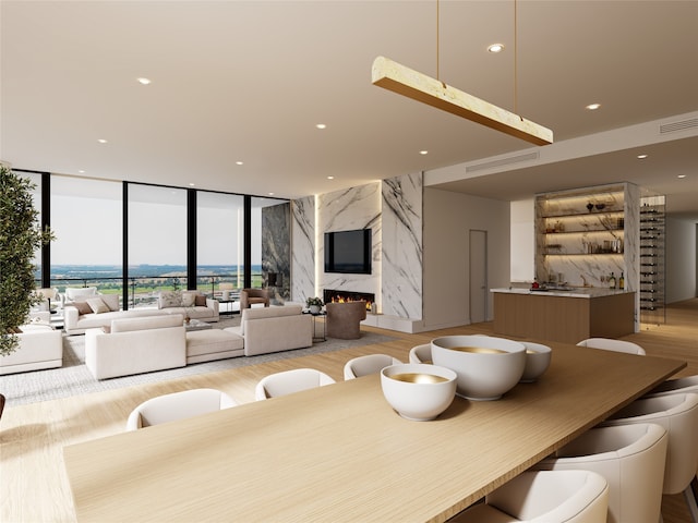 dining room with a high end fireplace, light hardwood / wood-style floors, and floor to ceiling windows