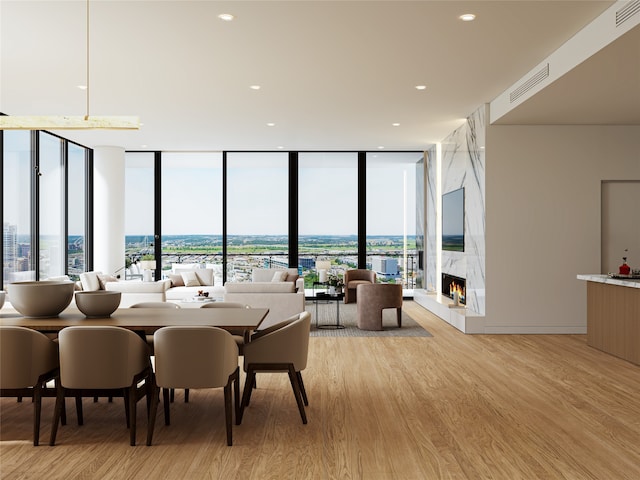 dining room with a premium fireplace, floor to ceiling windows, and light wood-type flooring