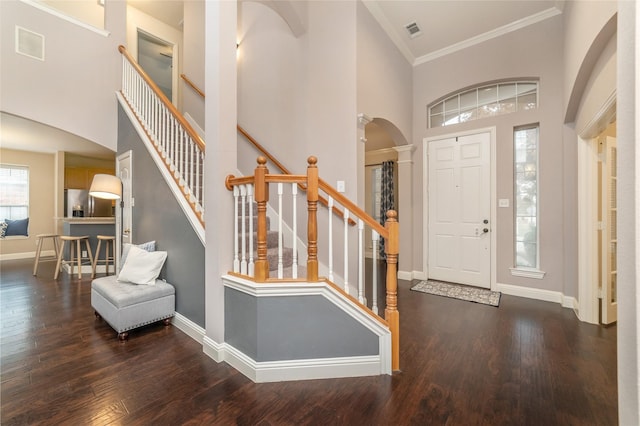 entryway featuring a high ceiling, crown molding, and dark wood-type flooring