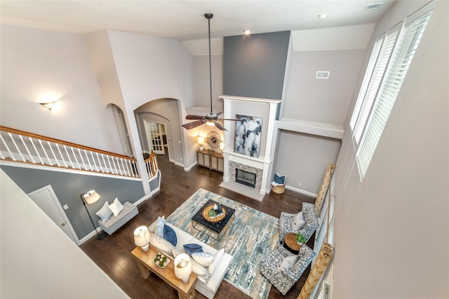 living room featuring ceiling fan, a stone fireplace, dark wood-type flooring, and high vaulted ceiling