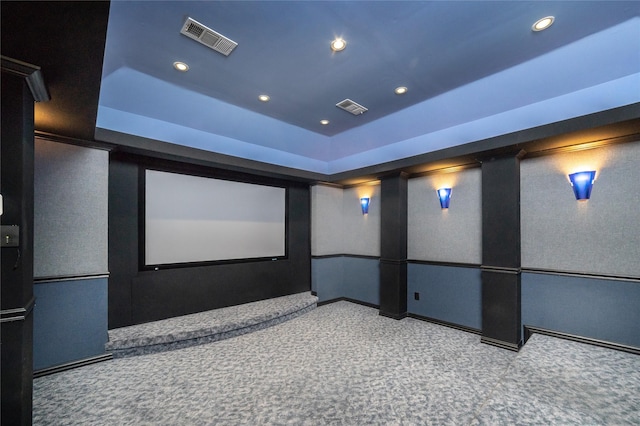 carpeted home theater room with a tray ceiling