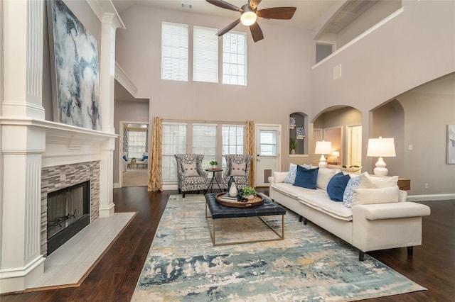 living room featuring a fireplace, ceiling fan, plenty of natural light, and dark wood-type flooring