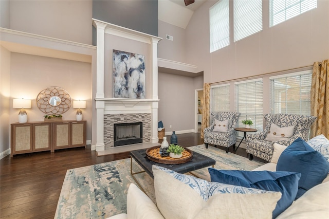 living room featuring a fireplace, a towering ceiling, and dark wood-type flooring