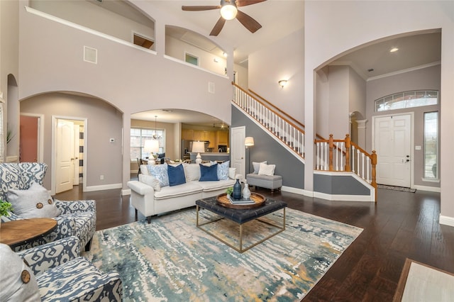 living room featuring dark hardwood / wood-style flooring, a towering ceiling, ceiling fan, and ornamental molding