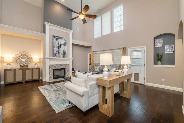 living room with ceiling fan, dark wood-type flooring, a healthy amount of sunlight, and a high ceiling