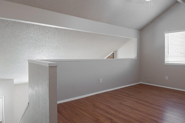 unfurnished room featuring a textured ceiling, lofted ceiling, and hardwood / wood-style flooring