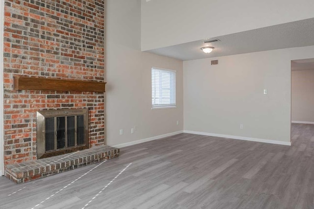 unfurnished living room with a fireplace, wood-type flooring, and a textured ceiling