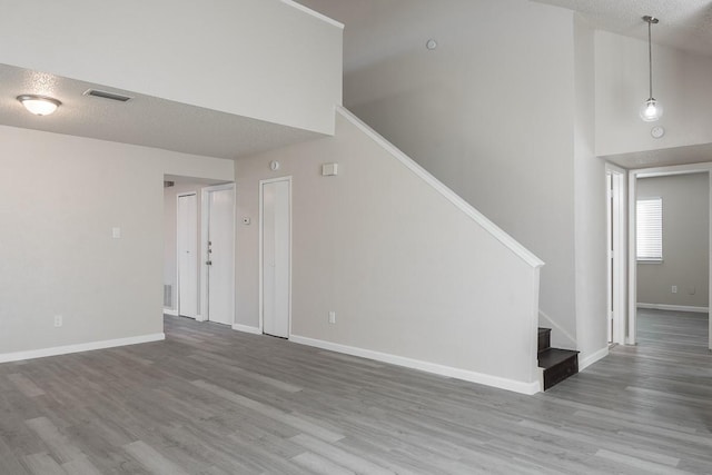 interior space featuring a towering ceiling, a textured ceiling, and hardwood / wood-style flooring