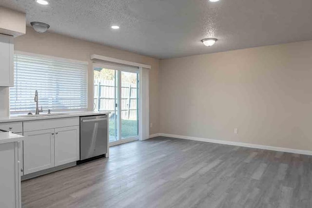 kitchen featuring sink, light hardwood / wood-style flooring, stainless steel dishwasher, a textured ceiling, and white cabinets