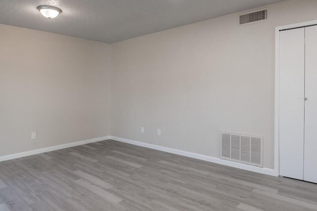 spare room with light hardwood / wood-style floors and a textured ceiling