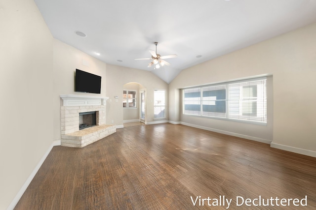1125 Appalachian Ln, Savannah, TX 76227 - unfurnished living room featuring ceiling fan, a fireplace with raised hearth, baseboards, arched walkways, and vaulted ceiling