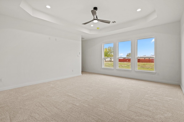 carpeted spare room featuring a raised ceiling and ceiling fan