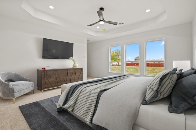 carpeted bedroom featuring a tray ceiling and ceiling fan