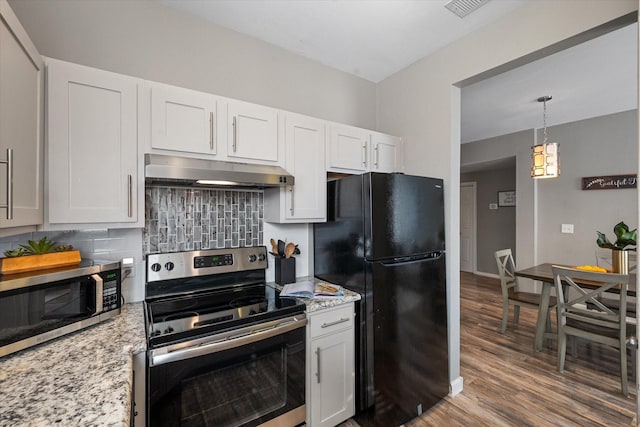 kitchen with wood-type flooring, appliances with stainless steel finishes, white cabinets, light stone countertops, and backsplash