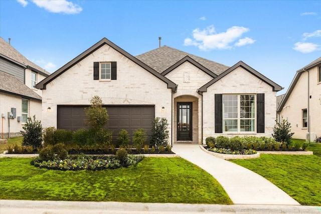 french country style house featuring a garage and a front yard