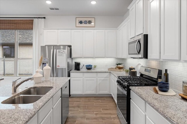 kitchen with sink, white cabinets, light wood-type flooring, and appliances with stainless steel finishes