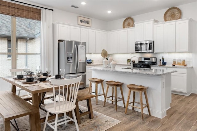 kitchen with white cabinets, stainless steel appliances, and light hardwood / wood-style floors