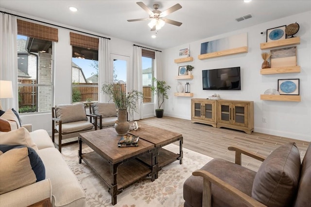 living room featuring ceiling fan, light hardwood / wood-style floors, and a wealth of natural light