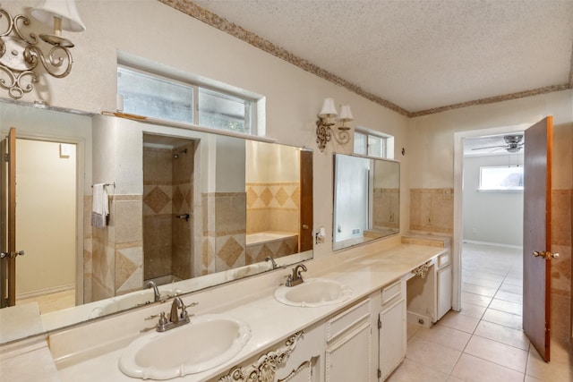 bathroom with vanity, tile patterned flooring, ceiling fan, tiled shower, and a textured ceiling