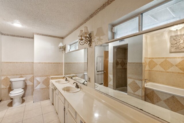 bathroom featuring a bathing tub, tile patterned floors, a textured ceiling, vanity, and tile walls