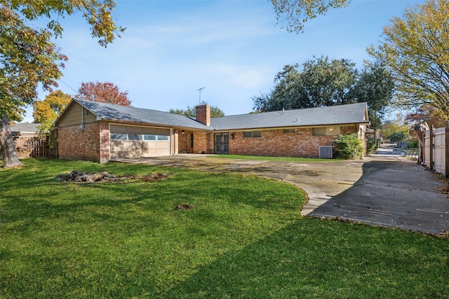 rear view of property with a lawn, a garage, and central AC