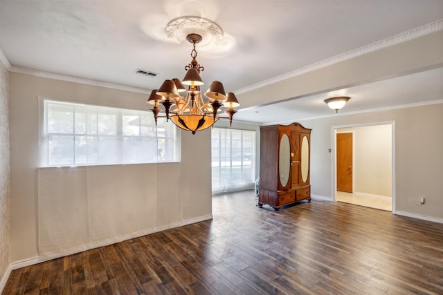 unfurnished room featuring plenty of natural light, dark hardwood / wood-style flooring, crown molding, and an inviting chandelier