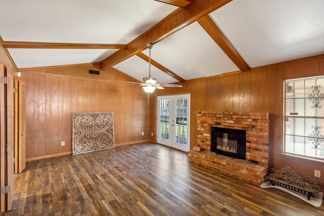 unfurnished living room with wooden walls, vaulted ceiling with beams, dark hardwood / wood-style floors, and a healthy amount of sunlight