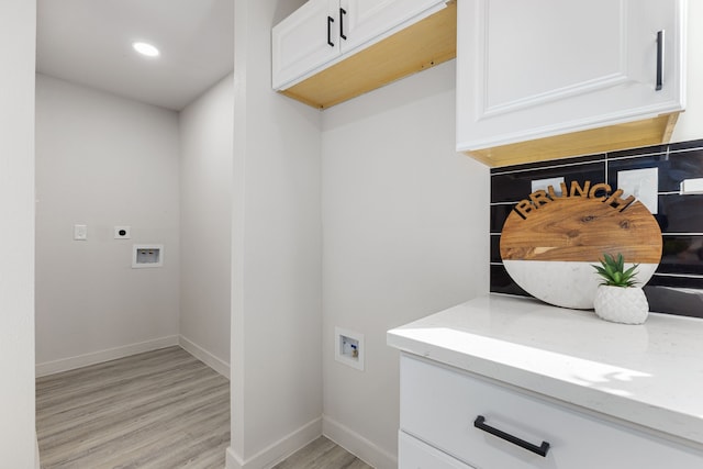 clothes washing area featuring electric dryer hookup, light hardwood / wood-style floors, cabinets, and hookup for a washing machine