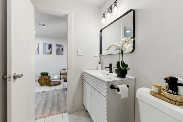 bathroom with wood-type flooring, vanity, and toilet