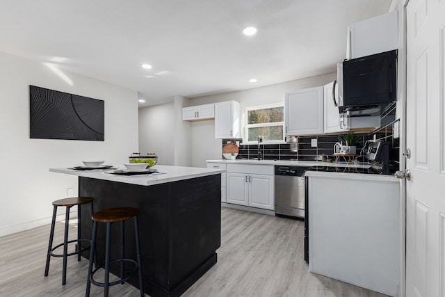 kitchen with a kitchen breakfast bar, light wood-type flooring, stainless steel dishwasher, white cabinets, and a center island