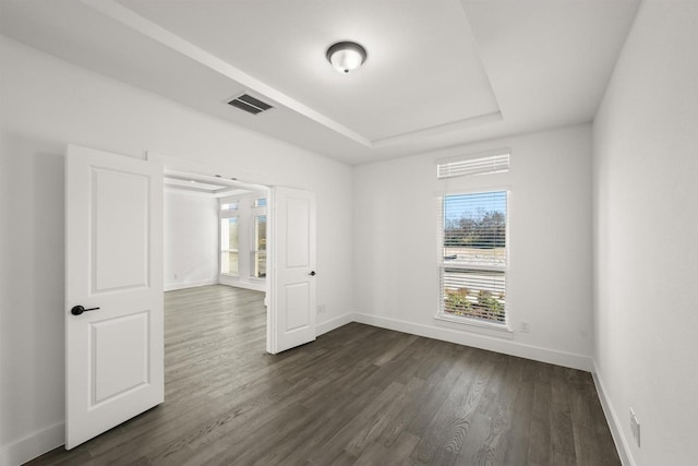 spare room with dark wood-type flooring and a tray ceiling