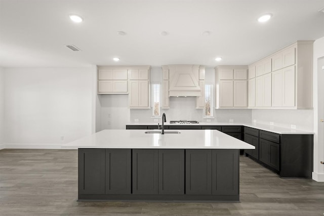 kitchen featuring white cabinetry, gas cooktop, dark hardwood / wood-style floors, a kitchen island with sink, and sink