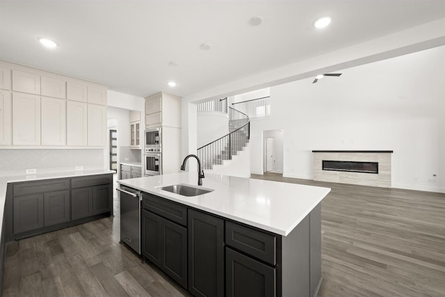 kitchen featuring a center island with sink, sink, white cabinetry, appliances with stainless steel finishes, and dark wood-type flooring