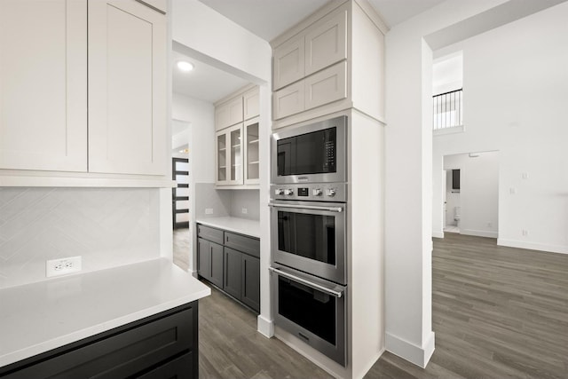 kitchen with white cabinetry, dark hardwood / wood-style floors, stainless steel double oven, and built in microwave