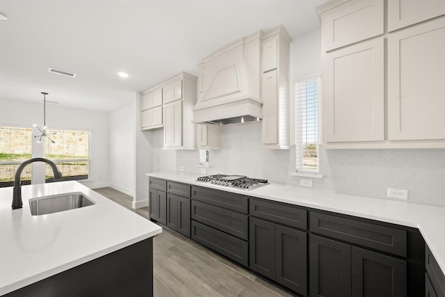 kitchen featuring an inviting chandelier, light wood-type flooring, stainless steel gas cooktop, white cabinets, and sink