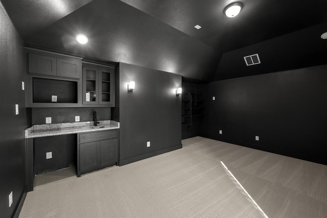 kitchen with light stone countertops, sink, light carpet, and vaulted ceiling