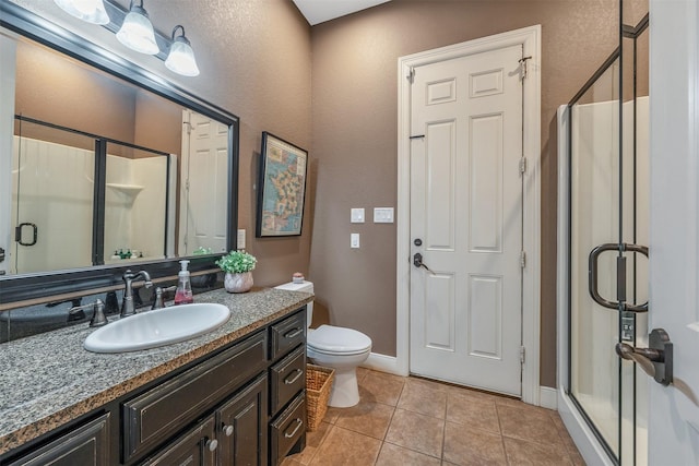 bathroom with tile patterned floors, vanity, a shower with shower door, and toilet