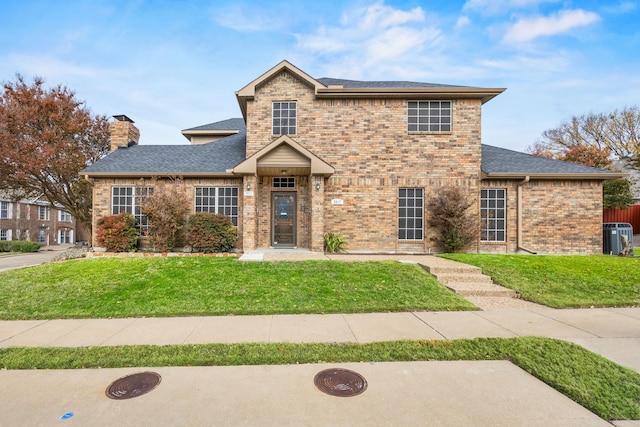 view of front of property with a chimney, a shingled roof, a front lawn, and brick siding