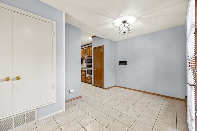 unfurnished room featuring light tile patterned floors, visible vents, and baseboards