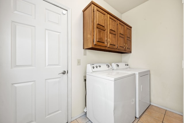 laundry area with baseboards, cabinet space, light tile patterned flooring, and washing machine and clothes dryer