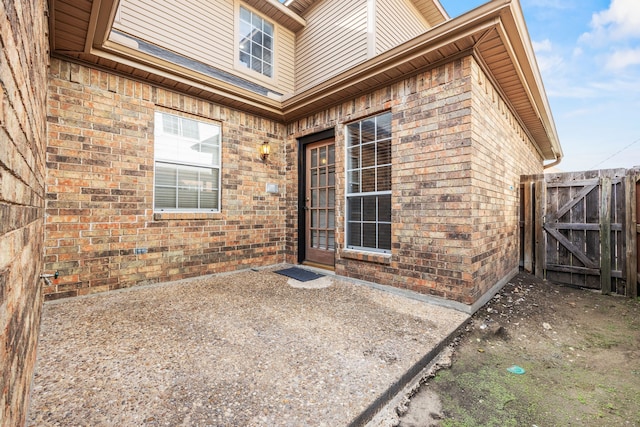 exterior space with a patio, brick siding, fence, and a gate