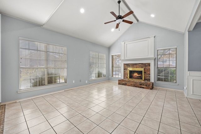 unfurnished living room with beam ceiling, ceiling fan, a fireplace, and light tile patterned floors