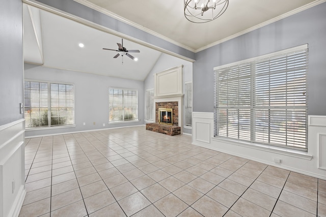 unfurnished living room featuring vaulted ceiling, light tile patterned floors, ornamental molding, ceiling fan with notable chandelier, and a fireplace