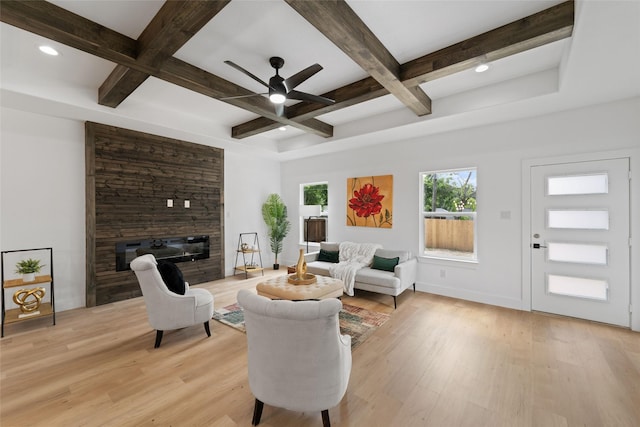 living room featuring beam ceiling, a large fireplace, light hardwood / wood-style floors, and coffered ceiling