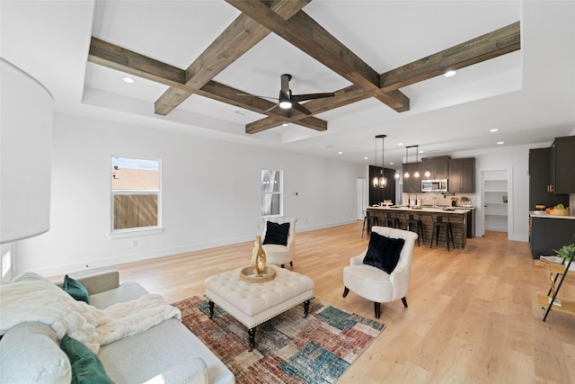 living room with coffered ceiling, ceiling fan with notable chandelier, beam ceiling, and light hardwood / wood-style flooring