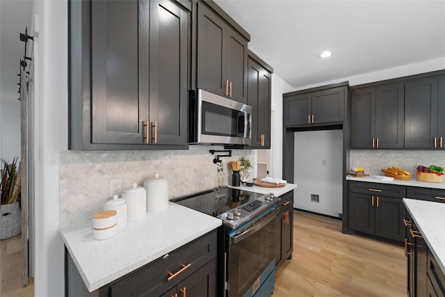 kitchen with appliances with stainless steel finishes, tasteful backsplash, and light hardwood / wood-style flooring