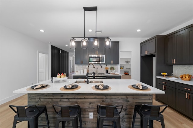 kitchen featuring tasteful backsplash, a center island with sink, and light wood-type flooring